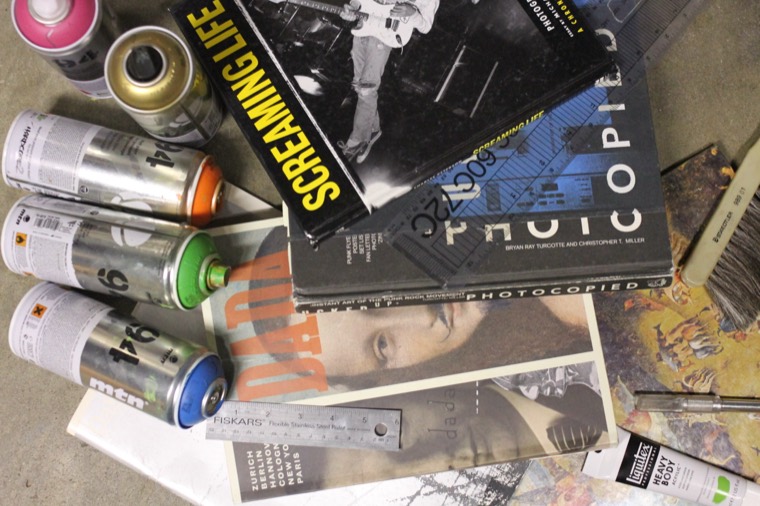 Spray paint cans, photocopies and books on a studio table