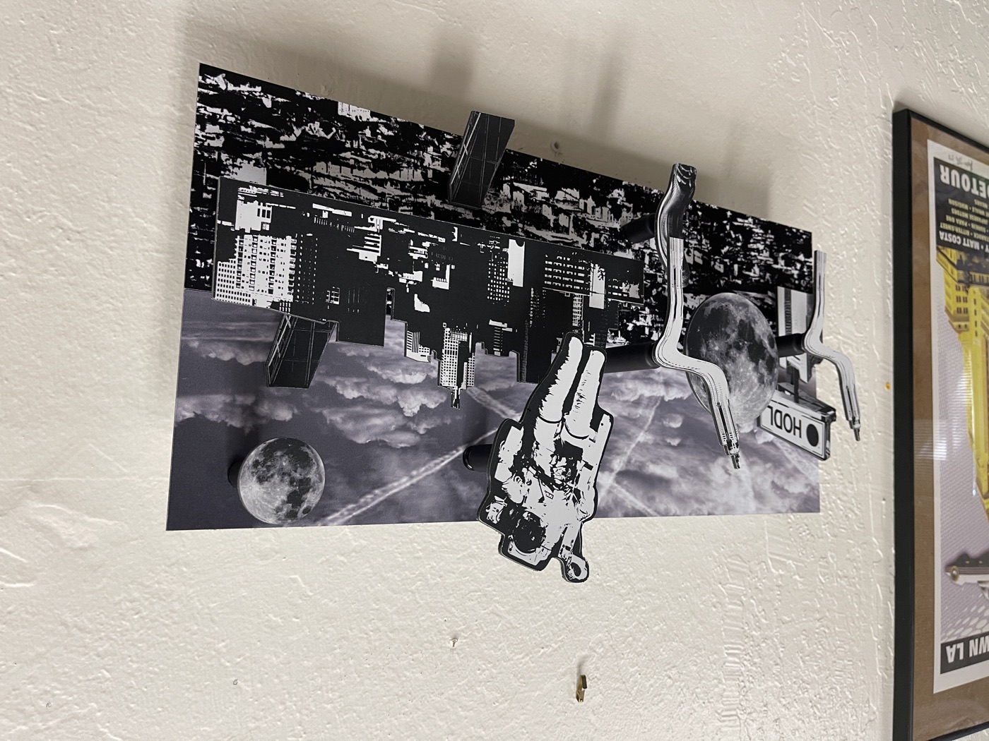 Layout seen at an angle: sky over a city, the astronaut breaking the top edge and the HODL billboard tucked at the left behind the moon